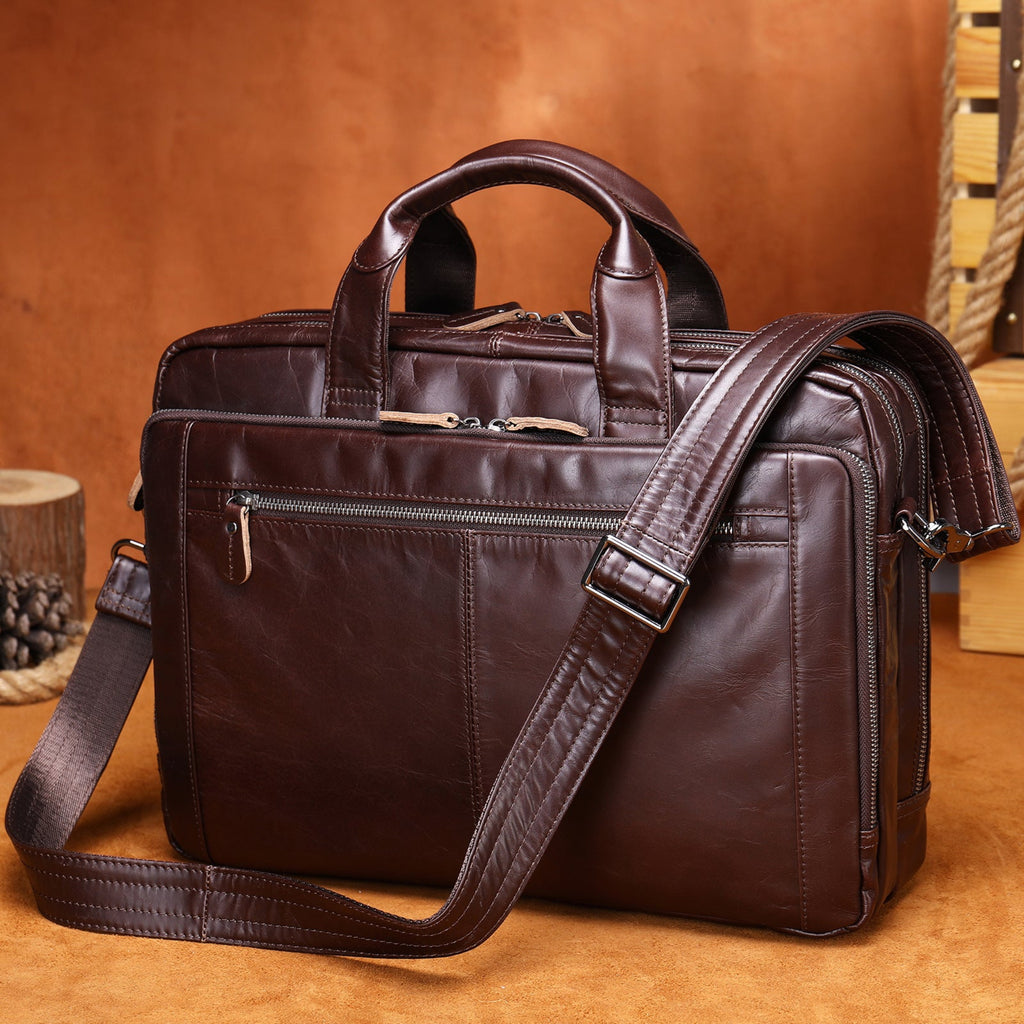 Brown leather briefcase with shoulder strap on a wooden surface