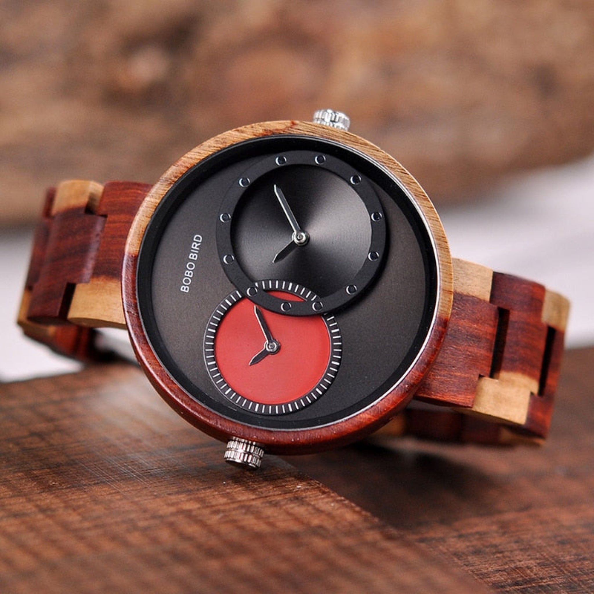 Wooden watch with black and red face on a wooden surface