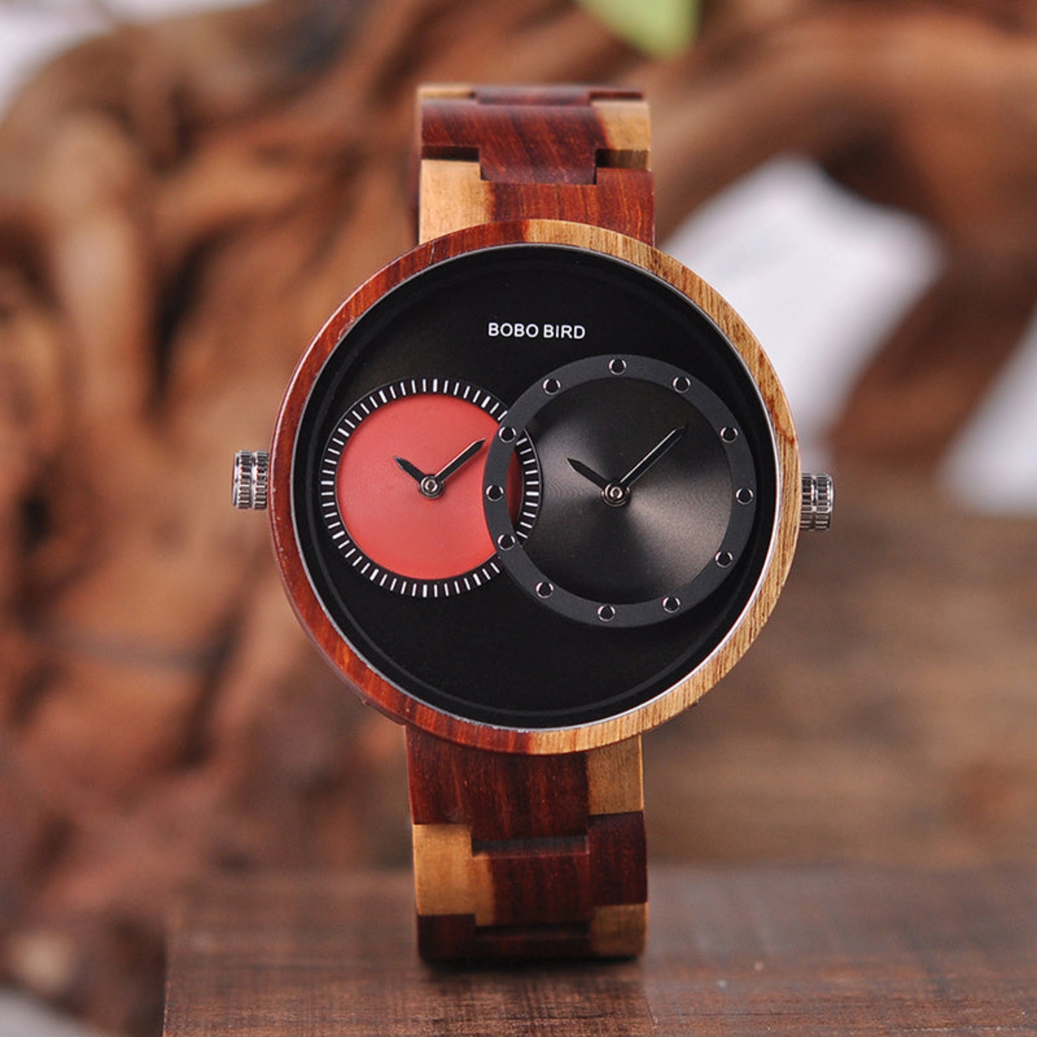 Wooden watch with red and black face on a wooden surface