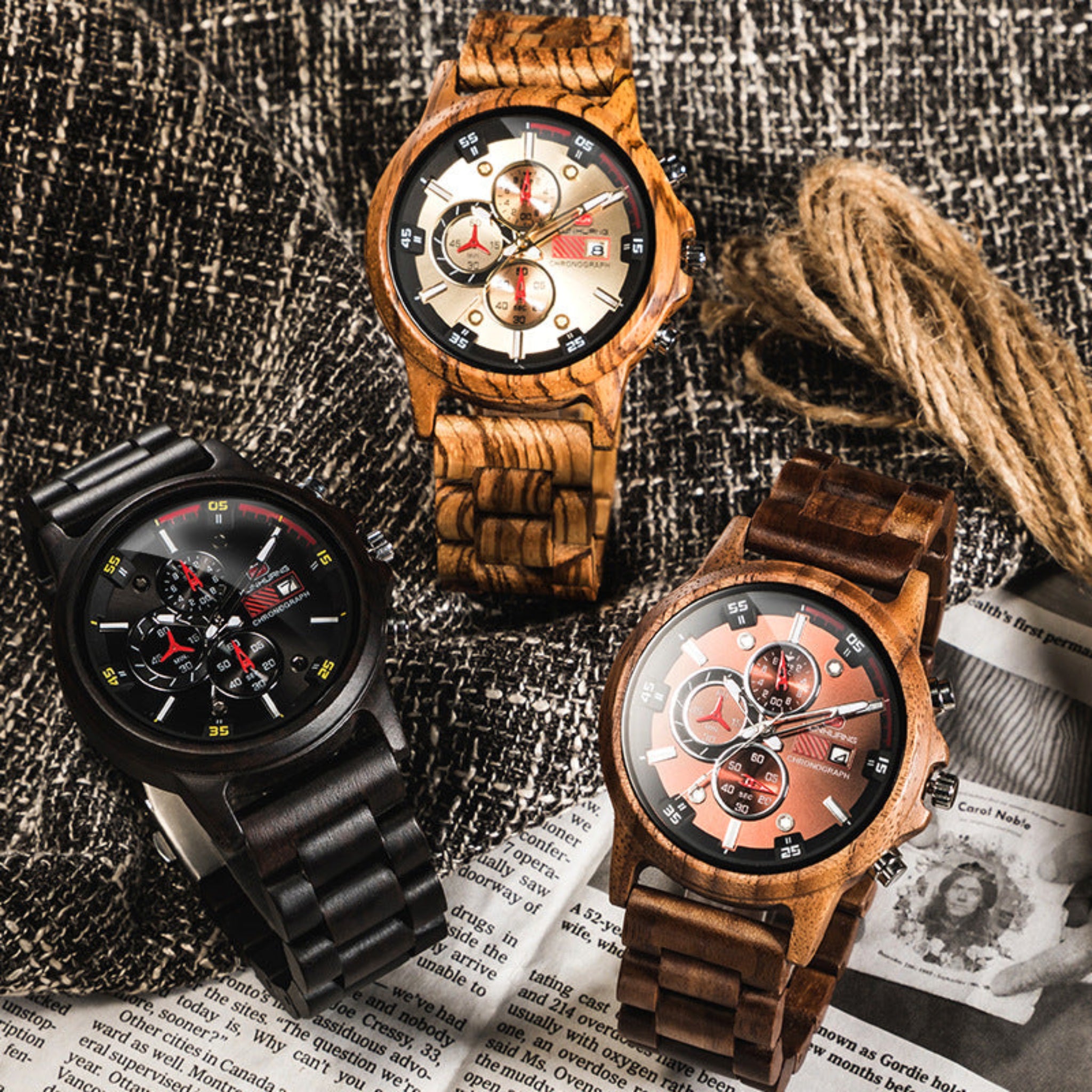Three wooden watches on a textured surface with newspaper