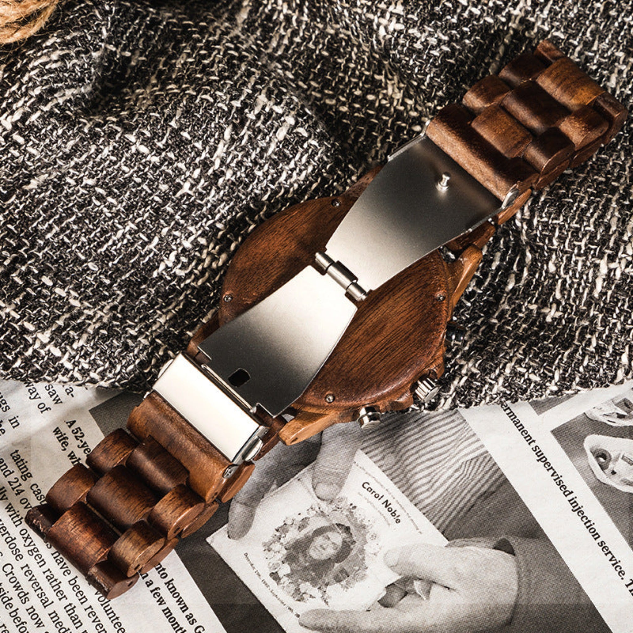 Wooden watch strap open clasp on a textured surface with a magazine underneath