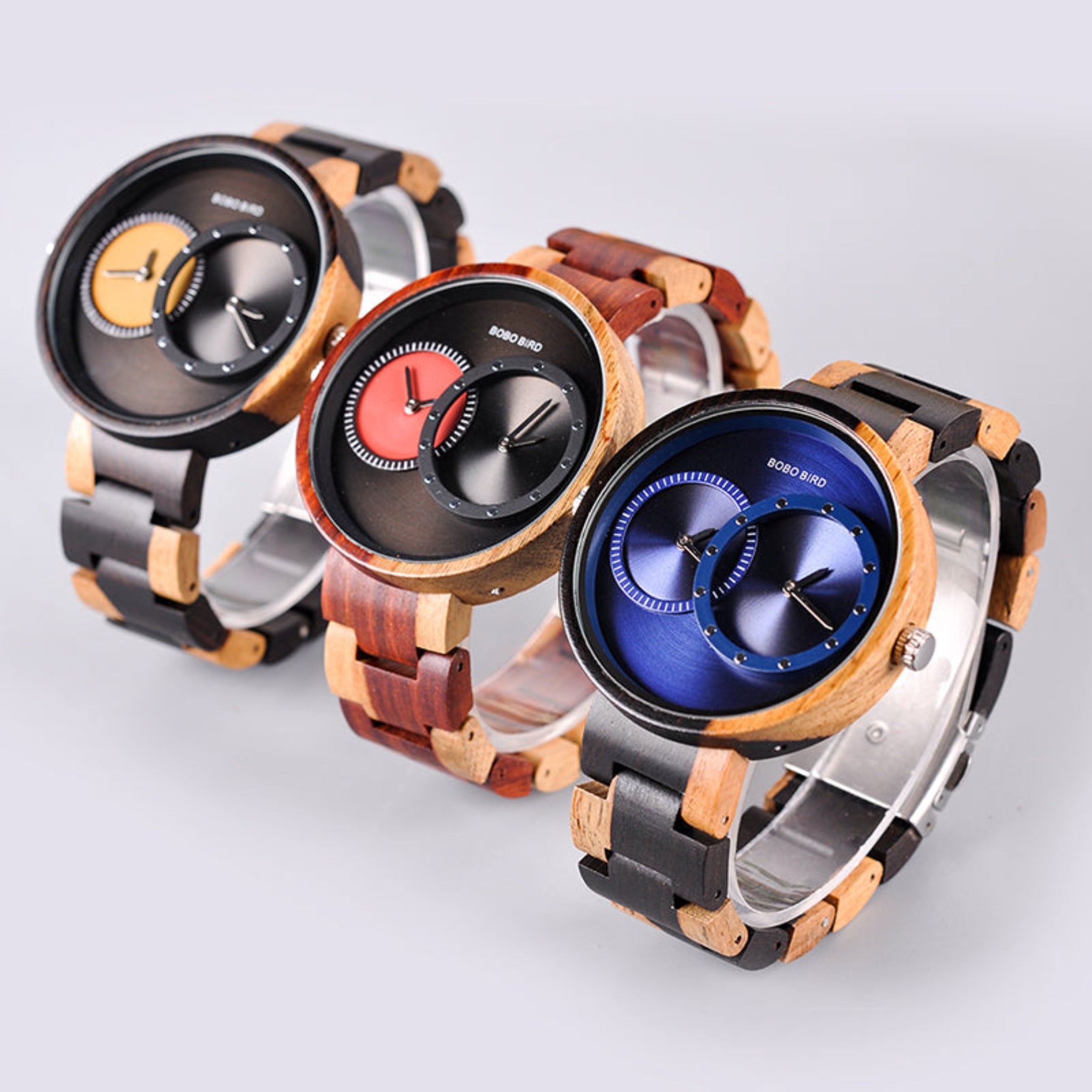 Three wooden watches with different color combinations on a light gray background