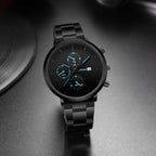 Black steel watch with blue dial on a desk